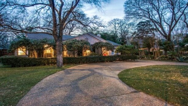 A residential house with a driveway leading to the front door, surrounded by trees and a well-maintained lawn. - Dallas Love Field Bluffview Bluebonnet Road Bungalow (Dallas)