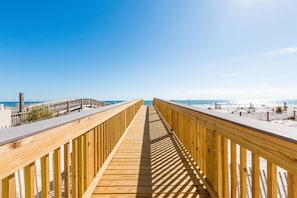 A wooden boardwalk leading to a beach with a clear sky.