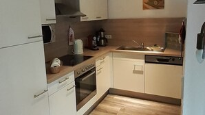 A modern kitchen with white cabinets, a wooden countertop, a built-in oven, and a sink. - "Moor & Meer" comfort apartment with terrace, garden, wheelchair accessible, dog welcome (Wiesmoor)