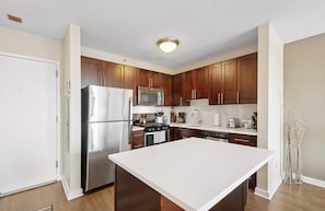 A modern kitchen with wooden cabinets, stainless steel appliances, and a large island. - 53 Floor MagMile Penthouse Views, Balcony, Pool (Chicago)