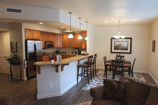 A modern kitchen with wooden cabinets, a central island, and pendant lighting.