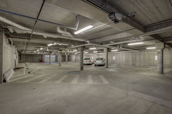 A multi-level parking garage with concrete pillars, fluorescent lighting, and a few parked cars. - Beautiful central downtown condo close to everything! Sun&Ski Condo  (Leavenworth)