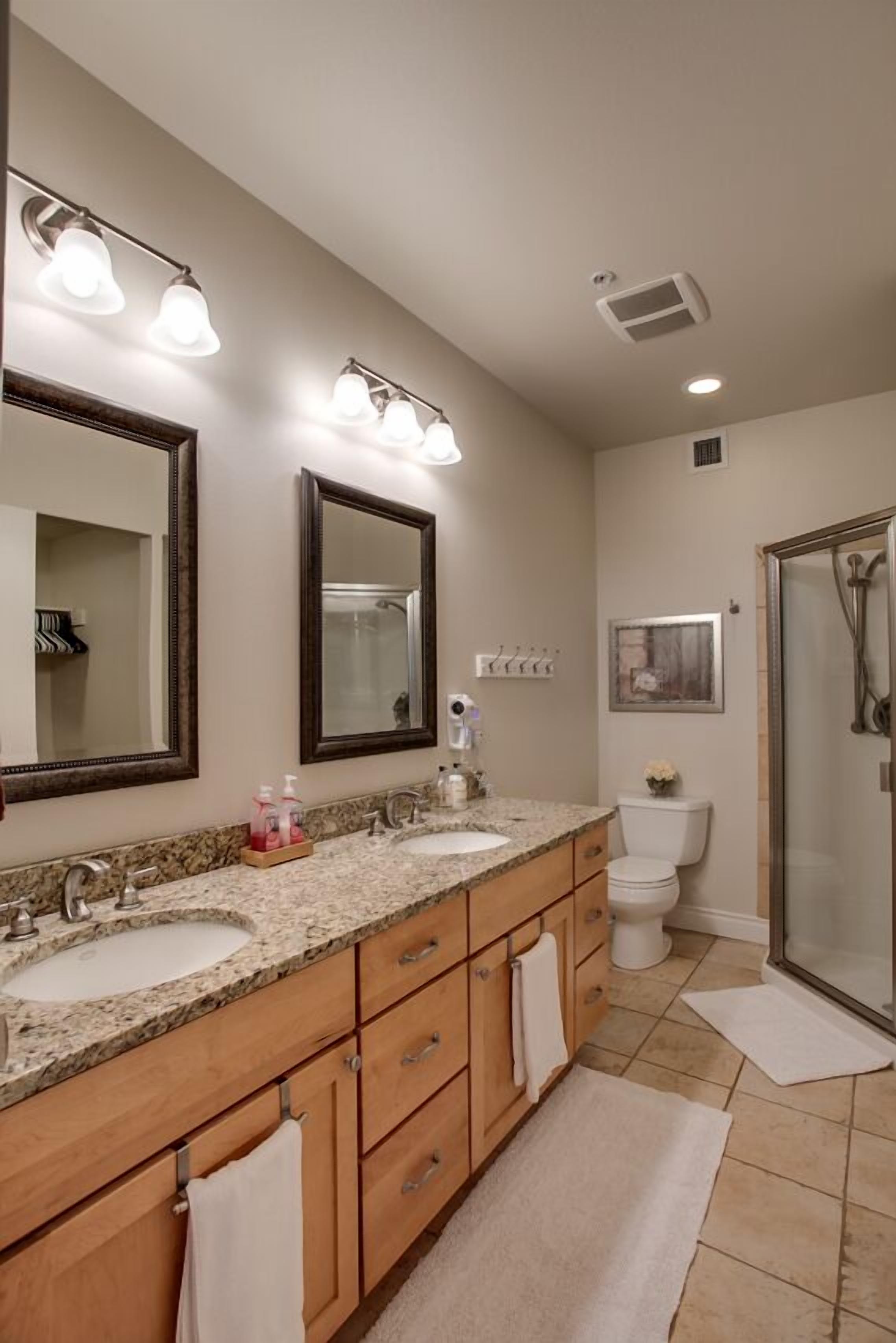 A bathroom with two sinks, a large mirror, and a shower.