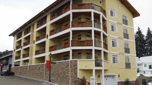 A multi-story building with balconies, a stone base, and a garage. - Beautiful central downtown condo close to everything! Sun&Ski Condo  (Leavenworth)