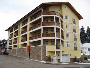 A multi-story building with balconies, a stone base, and a garage.