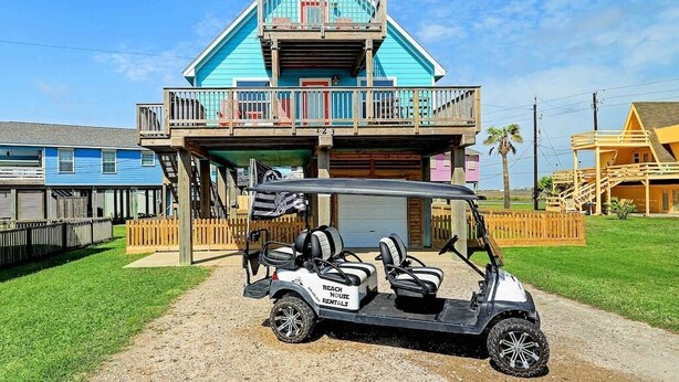 Un edificio a due piani con un balcone, un carrello da golf e un recinto in legno.