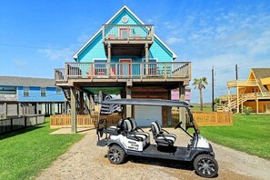 Un bâtiment à deux étages doté d’un balcon, d’une voiturette de golf et d’une clôture en bois.