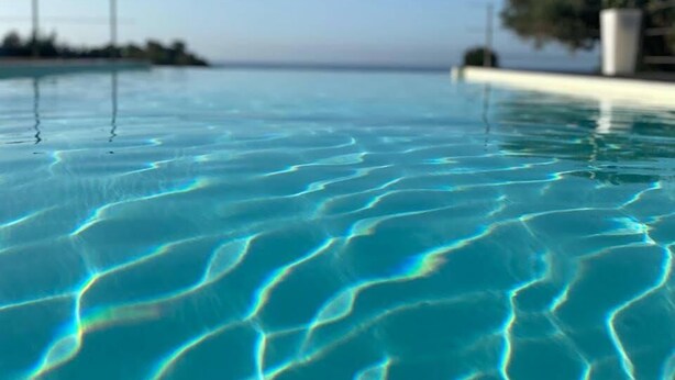On aperçoit clairement une piscine, avec des motifs visibles sur la surface de l’eau et un horizon lointain.