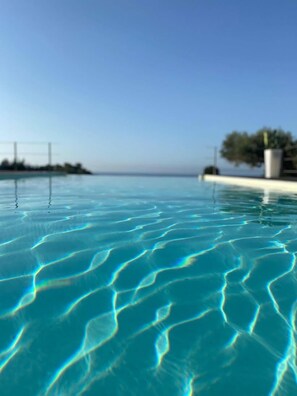 On aperçoit clairement une piscine, avec des motifs visibles sur la surface de l’eau et un horizon lointain.