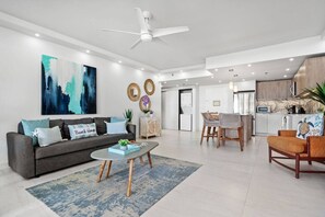 A modern living room with a grey sofa, coffee table, and a dining area with chairs.