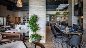 A modern restaurant with high ceilings, exposed beams, and a mix of seating arrangements including tables and booths.