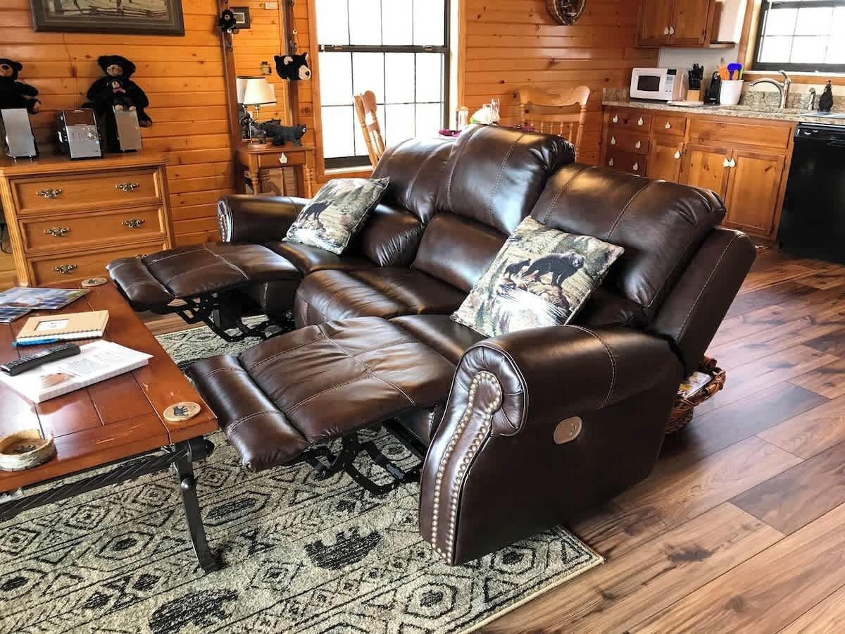 A leather sofa with a matching ottoman, a wooden coffee table, and a patterned rug.