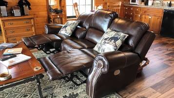 A leather sofa with a matching ottoman, a wooden coffee table, and a patterned rug.