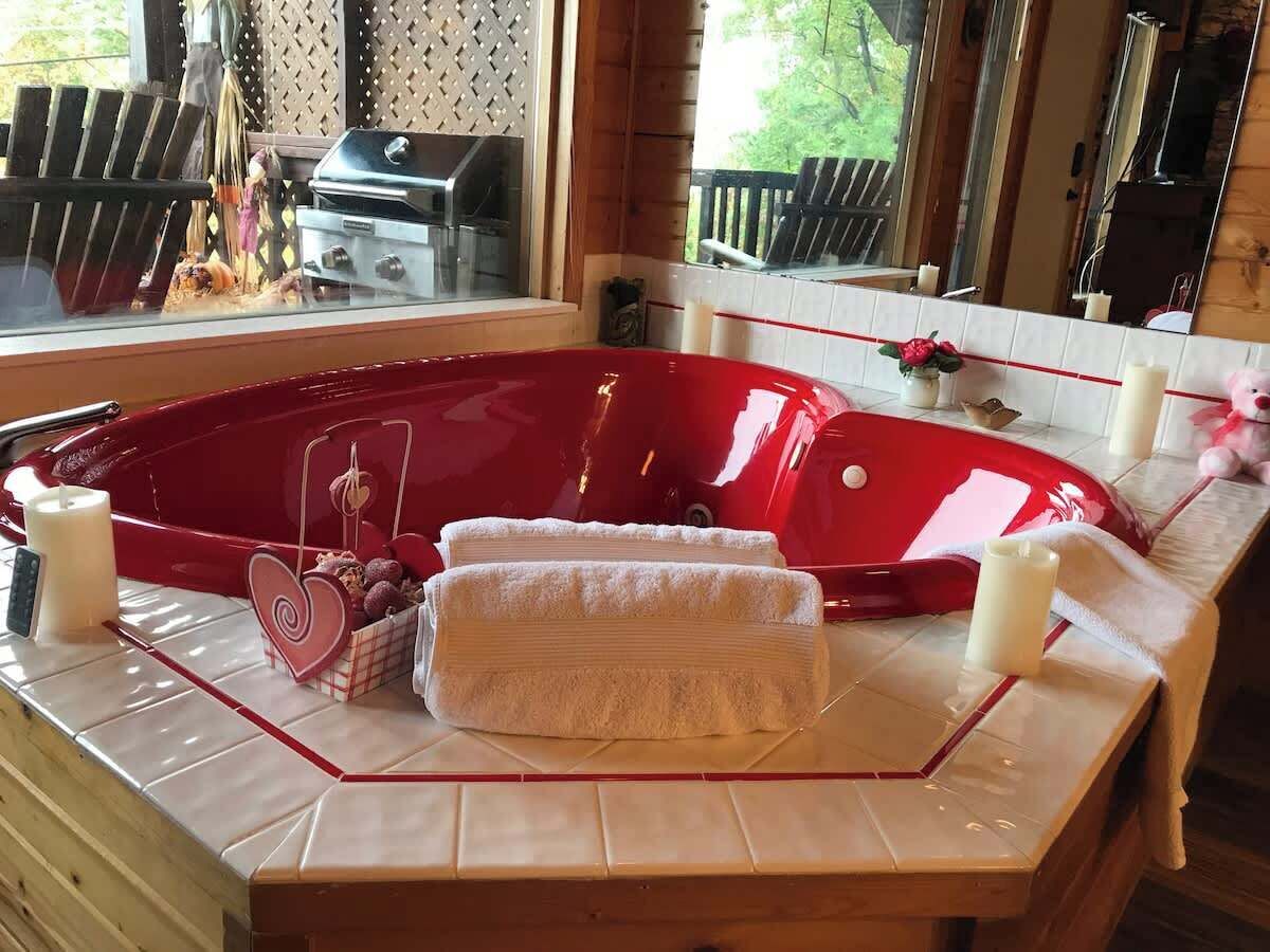A red hot tub with towels and candles on a tiled countertop.