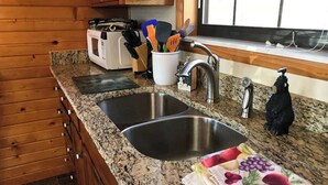 A kitchen with granite countertops, a double sink, wooden cabinets, and a window with blinds. - Honeymoon spot. Romantic. Great views. Private (Gatlinburg)