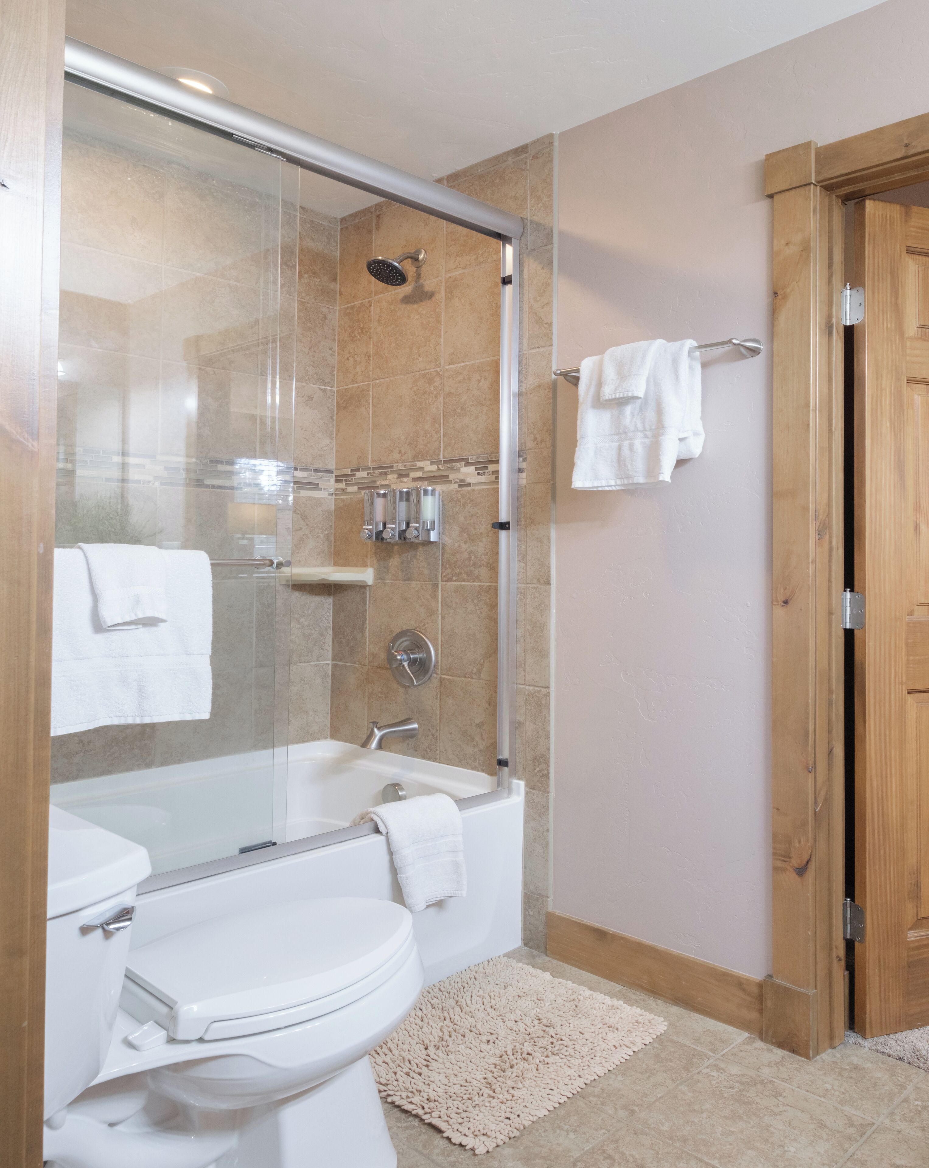 Un baño moderno con ducha de mampara de vidrio, inodoro blanco y bañera.