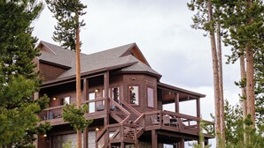 A multi-level wooden cabin with a balcony, surrounded by trees and rocks. - Epic Views! Luxe Cabin near RMNP, Trails & Fishing, and #1 Ski Resort in US (Tabernash)