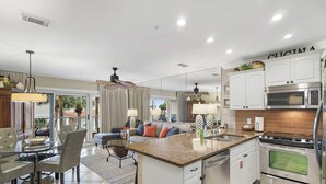 Una cocina moderna con armarios blancos, una isla central y electrodomésticos de acero inoxidable.
