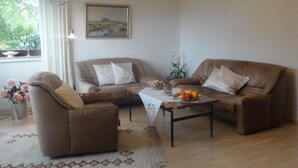 Un salon avec deux canapés marron, une table basse et un lustre.