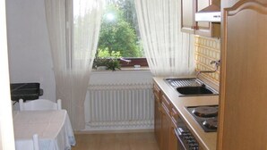 Une petite cuisine avec une fenêtre, un évier et une cuisinière.