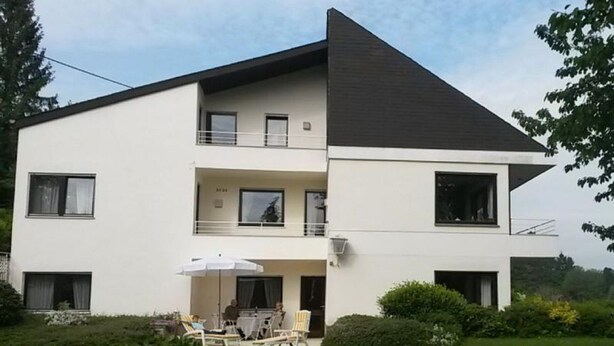 Un bâtiment moderne à deux étages, doté d’un toit plat et d’un balcon à l’étage supérieur.