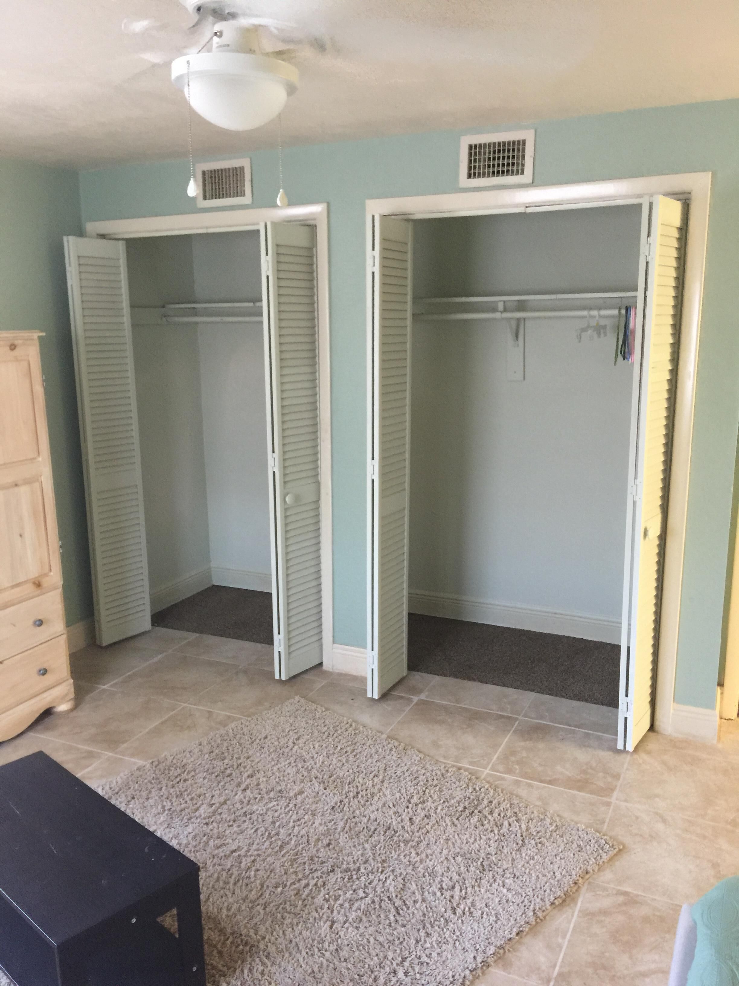 A room with two open closets, a wooden dresser, and a black table.