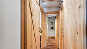 A wooden hallway with a staircase leading to a room with framed pictures on the wall.