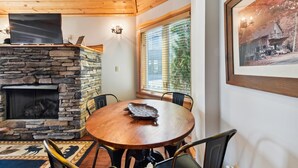 A cozy room with a stone fireplace, a round wooden table, and a framed picture on the wall.
