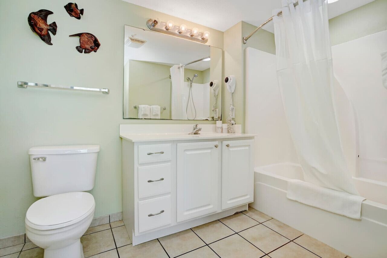 A bathroom with a toilet, a vanity with drawers, a mirror, a shower, and a bathtub.
