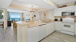 Une cuisine moderne avec des meubles blancs, un îlot central, un four à micro-ondes et un four traditionnel.