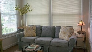 A living room with a gray sectional sofa, a small coffee table, a vase with flowers, and a lamp on a side table. - Winter Park charm. Close to Park Ave (Winter Park)