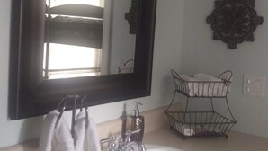 A bathroom with a white sink, a large mirror, and decorative wall sconces. - Winter Park charm. Close to Park Ave (Winter Park)