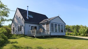 A two-story house with a covered porch and a large windowed room.