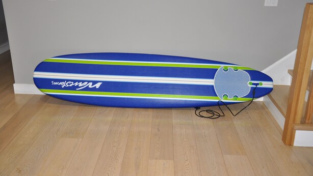 A blue and white striped surfboard with a green stripe and the word "Nukesurfing" on a wooden floor.