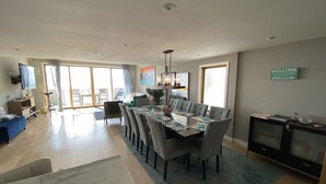 A spacious living area with a dining table, sofas, and a TV.