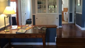 A dining area with a wooden table, chairs, and a lamp. There is a cabinet with glass doors in the background.