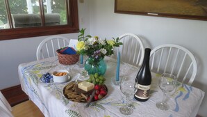 A dining table set with a floral tablecloth, a vase with flowers, a bottle of wine, and various snacks.
