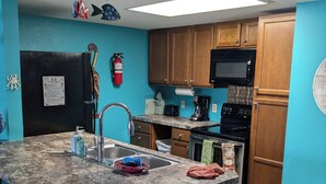 Una cocina con encimera de granito, electrodomésticos de acero inoxidable, armarios de madera y un extintor rojo.
