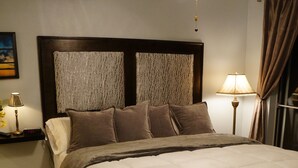 Ein ordentlich bezogenes Bett mit Kopfteil, einer Nachttischlampe und einem Nachttisch mit Lampe.