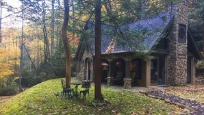 Eine Steinhütte mit Steinsschornstein, umgeben von einem Wald.