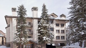 A multi-story hotel with a central entrance, surrounded by snow-covered trees. - Townsend Place 205 | 2BR Ski-In/Ski-Out Condo, Hot Tub (Avon)