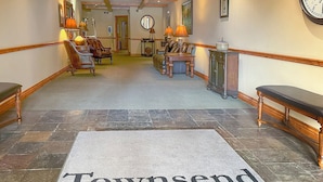 A hallway with a welcome mat reading "Townsend Place," wooden benches, and a clock on the wall. - Townsend Place 205 | 2BR Ski-In/Ski-Out Condo, Hot Tub (Avon)