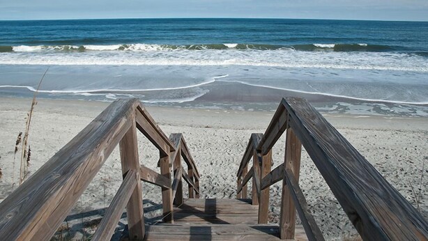 A wooden boardwalk leading to a beach with waves crashing onto the shore. - Pet Friendly, Oceanfront Downstairs Unit of Private Home, Pet Friendly (Fernandina Beach)