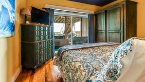 A bedroom with a bed, a dresser, a TV, and a view of the outside. - Pet Friendly, Oceanfront Downstairs Unit of Private Home, Pet Friendly (Fernandina Beach)
