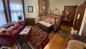 A traditional room with a red sofa, a wooden bed with a patterned bedspread, a small table, and a radiator.