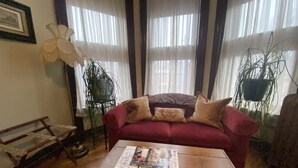 A living room with a red sofa, a wooden coffee table, and a plant.