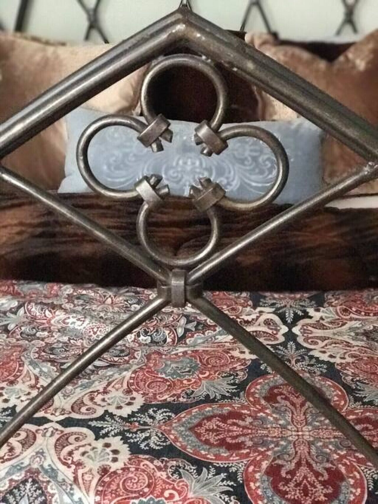 Un cadre de lit en métal orné d’un motif losangique, une couvre-lit à motifs et un coussin à fleurs.