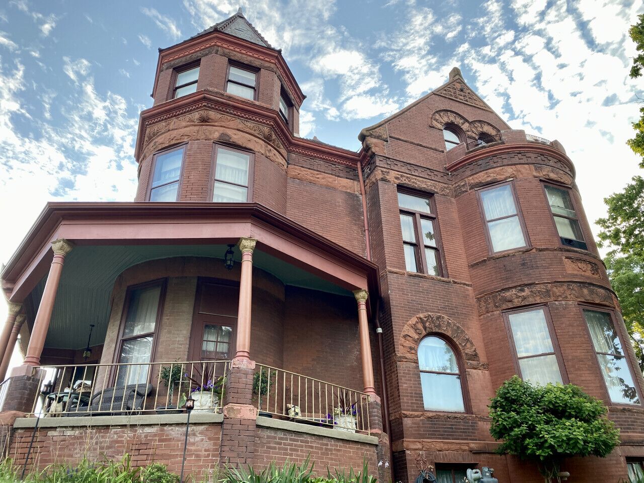 A large, historic brick building with a prominent tower and a wrap-around porch.