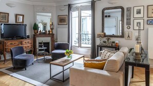 A living room with a sofa, armchairs, a coffee table, a TV, and a fireplace. - Wow Eiffel Tower View, Unbelievably Elegant & Spacious (Paris)