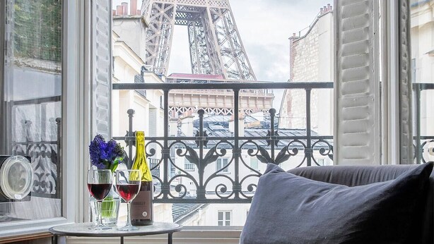 A room with a view of the Eiffel Tower, a round table with drinks, and a grey sofa. - Wow Eiffel Tower View, Unbelievably Elegant & Spacious (Paris)